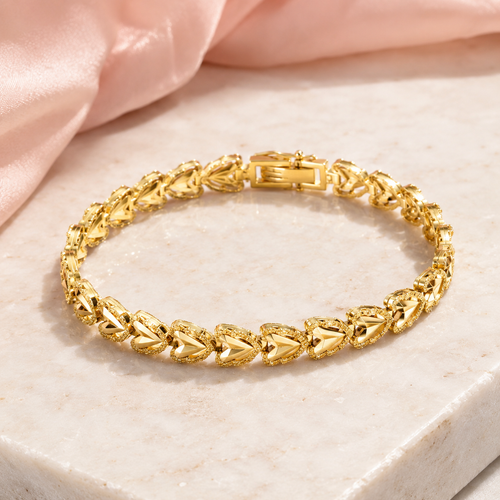 Gold plated statement bracelet with unique patterns on a marble surface.