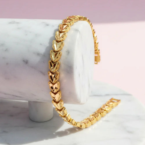 gold plated statement bracelet resting on a marble surface with unique patterns and shiny finish
